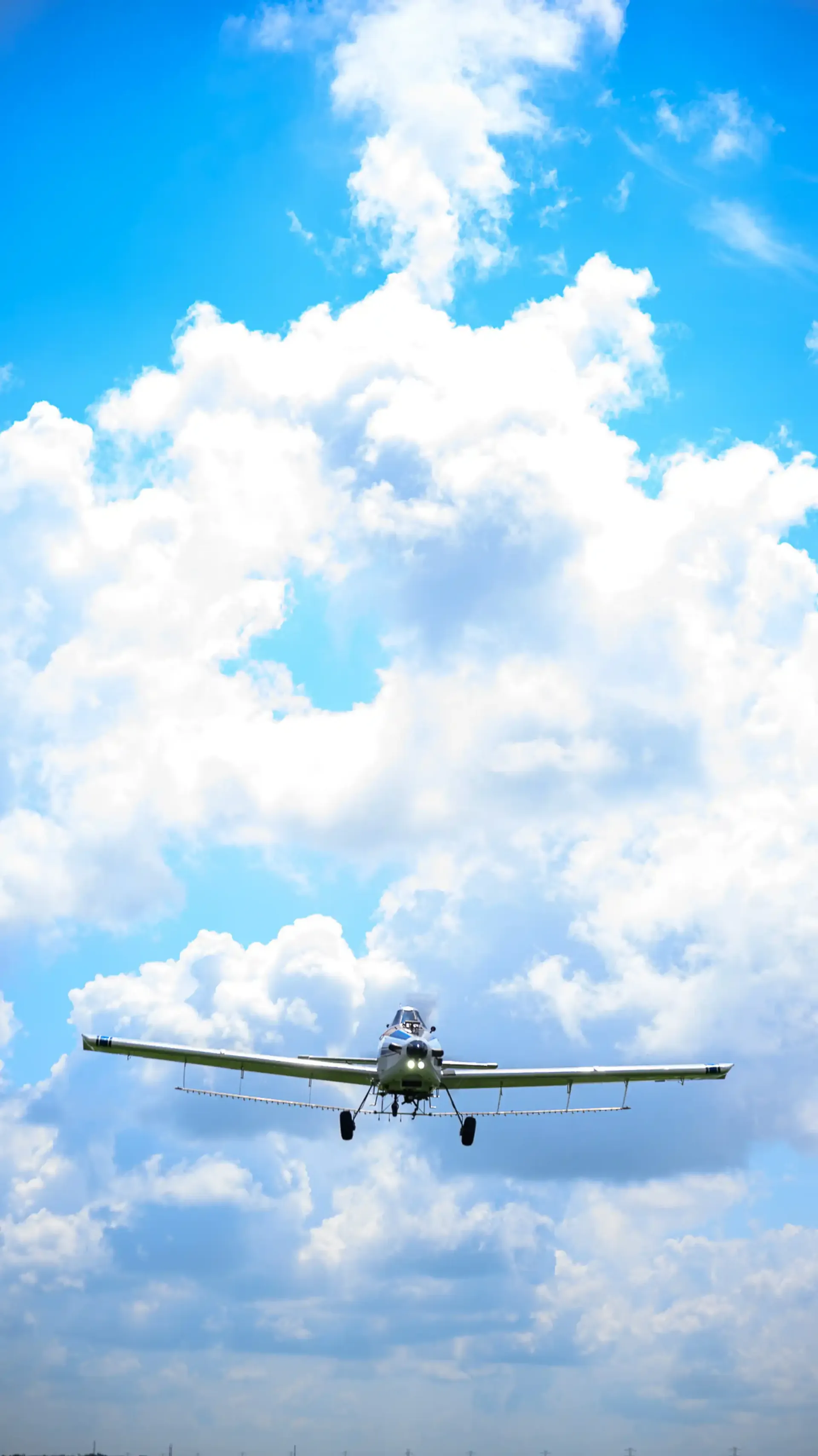 An agricultural aircraft flying head on through the clouds