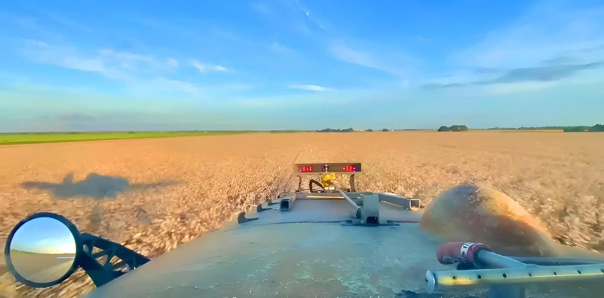 Pilot view over the hopper while flying low over a golden field