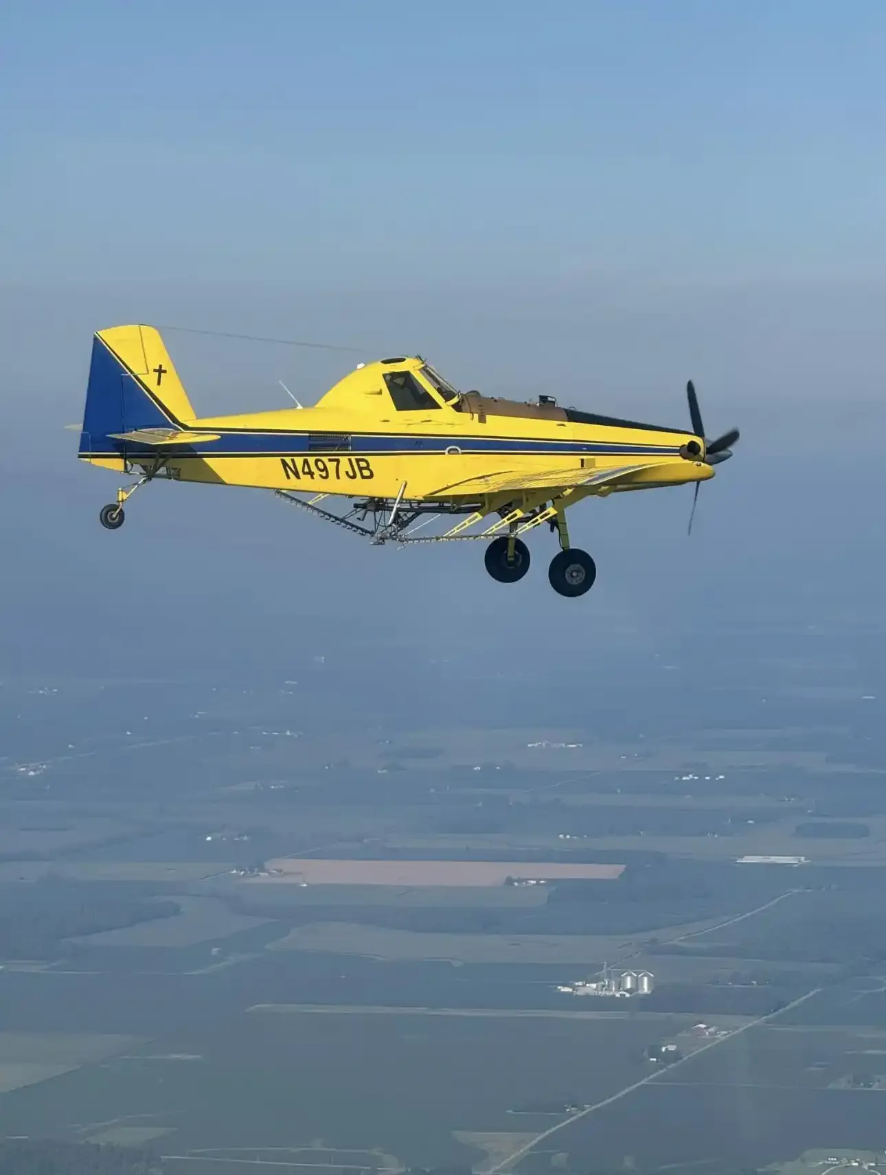 The yellow and blue Agri-Land Aviation aircraft in flight