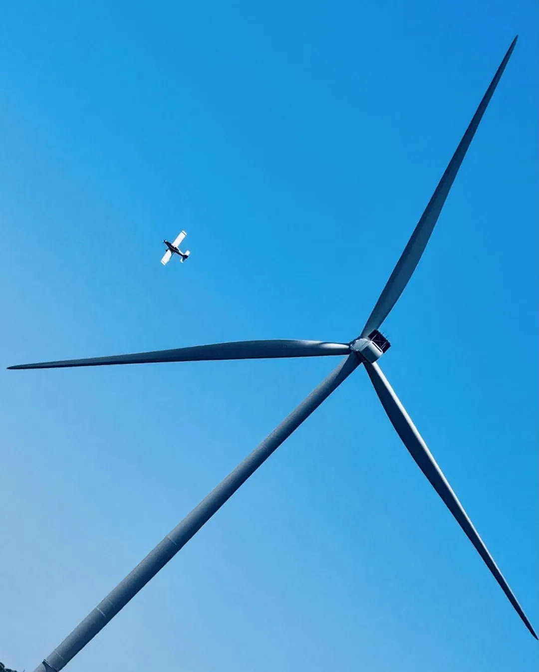 An Agri-Land Aviation aircraft near a wind turbine