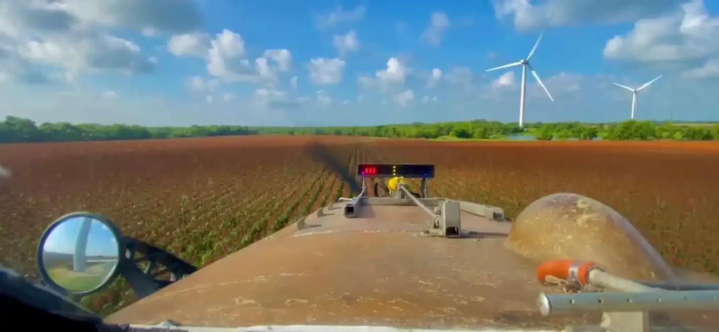 View from the cockpit over open farmland with wind turbines on the horizon